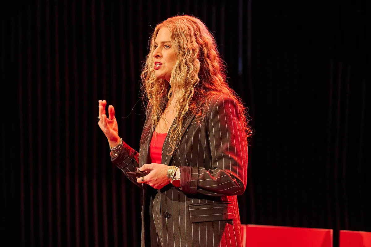 Dr Rebecca Chabot mid-talk on the red-lit TEDx Hobart stage